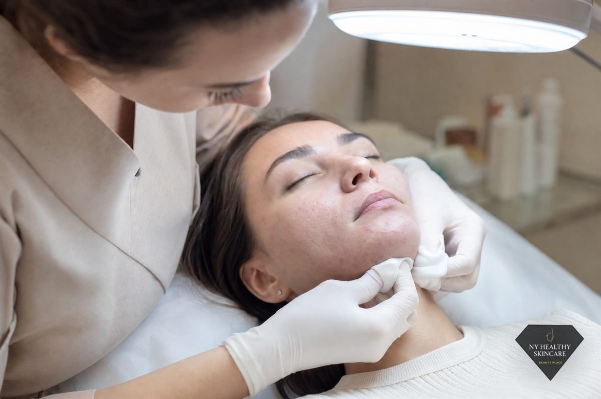 Esthetician performing careful extractions on acne-prone skin under a magnifying lamp in NYC