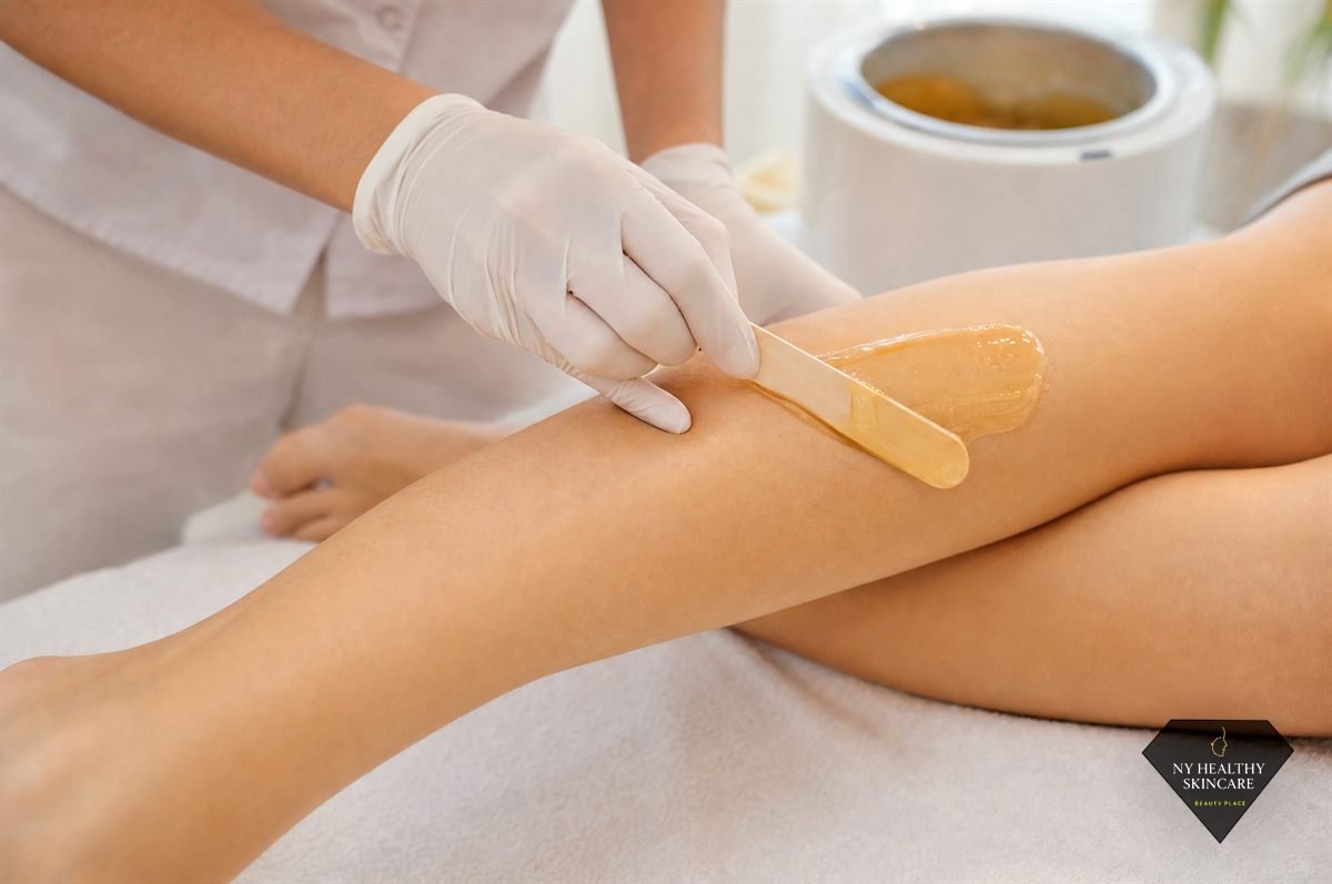 Esthetician applying warm hard wax to a client's lower leg during a waxing treatment in NYC